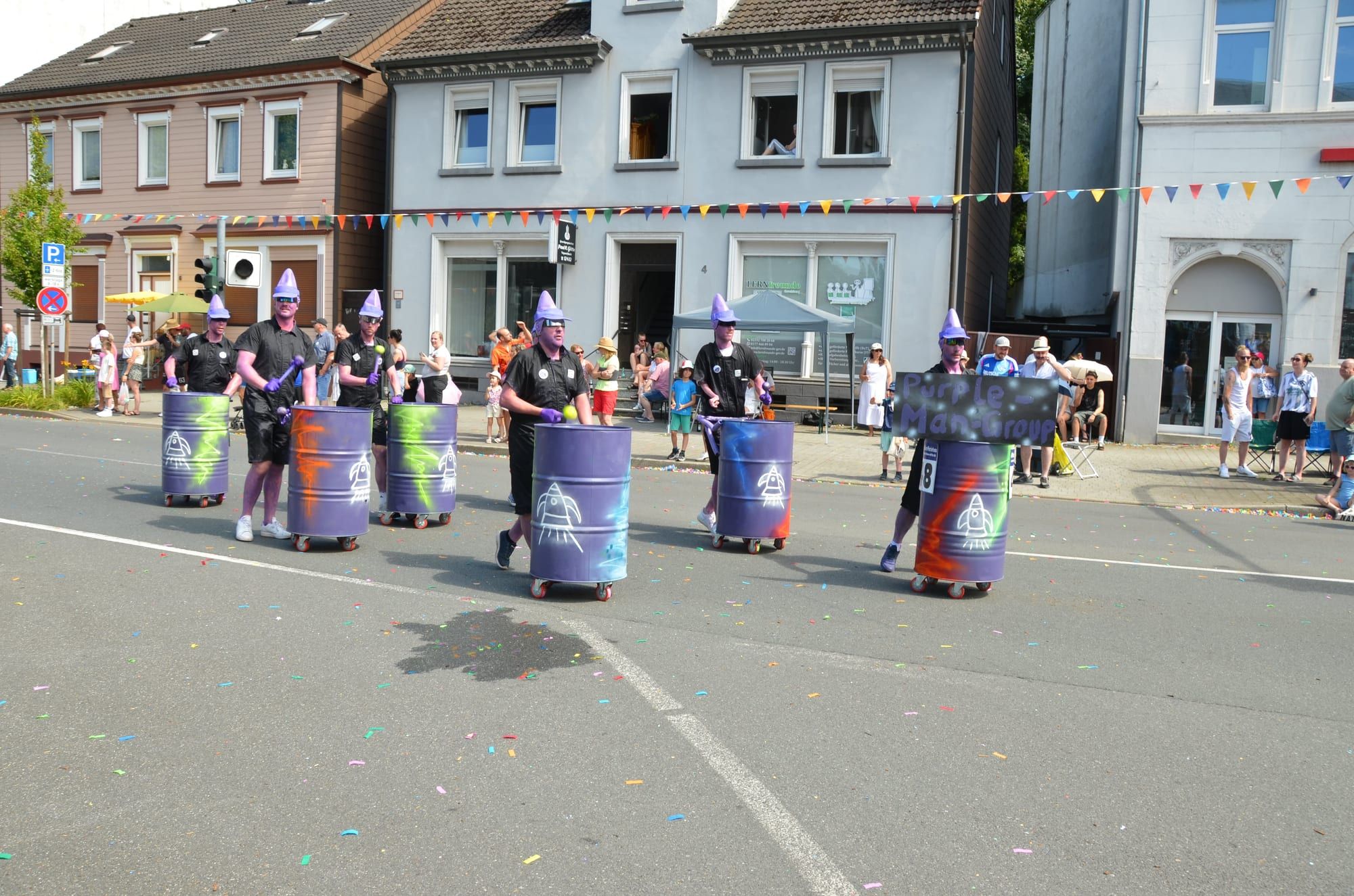 Die Fußgruppe „Purple Man Group“ trommelt auf lila Fässern